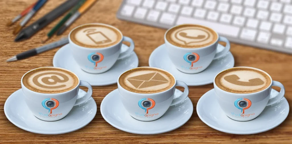 Tazzine di caffè con simboli di contatto nella schiuma su scrivania StudioPigna